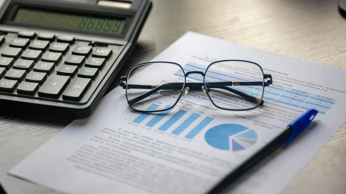 Financial statements with a calculator and glasses reviewed by a fractional CFO for an MSP