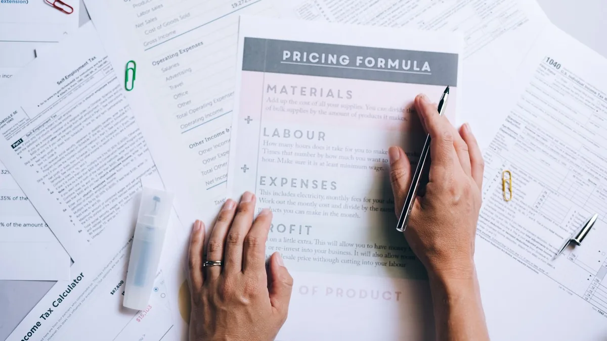 Hands reviewing a pricing formula worksheet, illustrating C4OS pricing