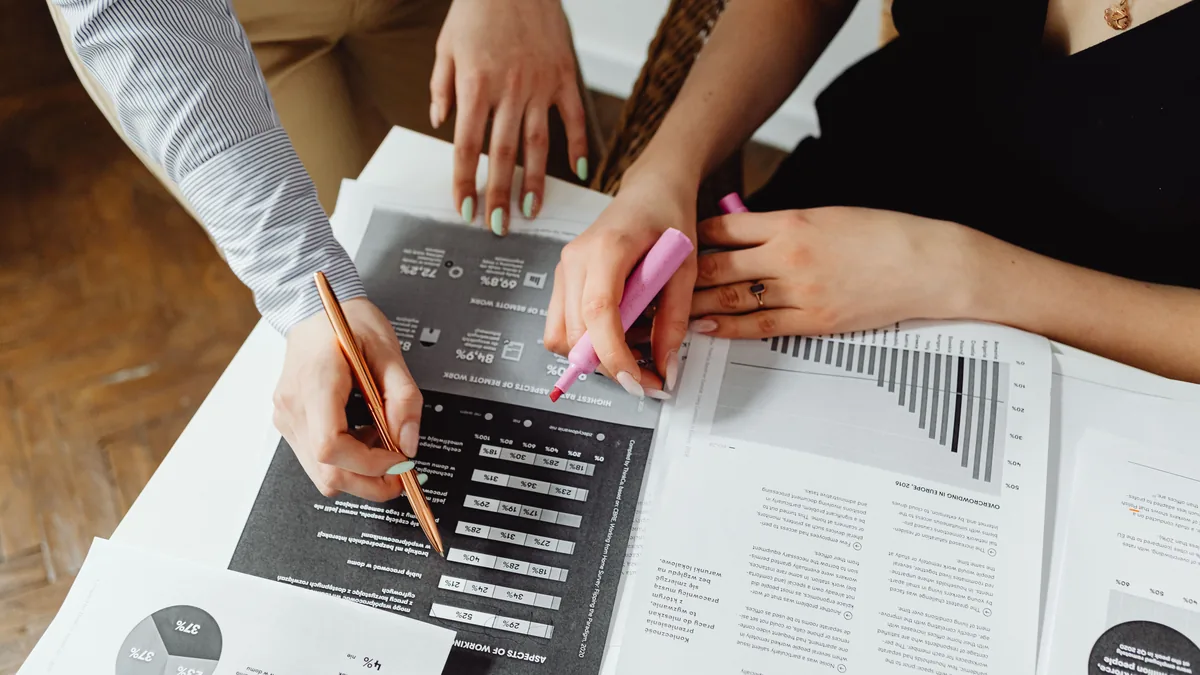 Two advisors marking up printed financial charts during an MSP exit readiness review with a fractional CFO
