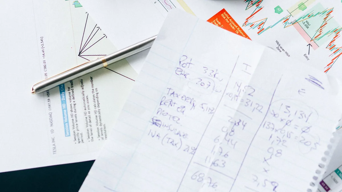 Magnifying glass over handwritten financial notes and numbers, reviewing MSP financial metrics closely