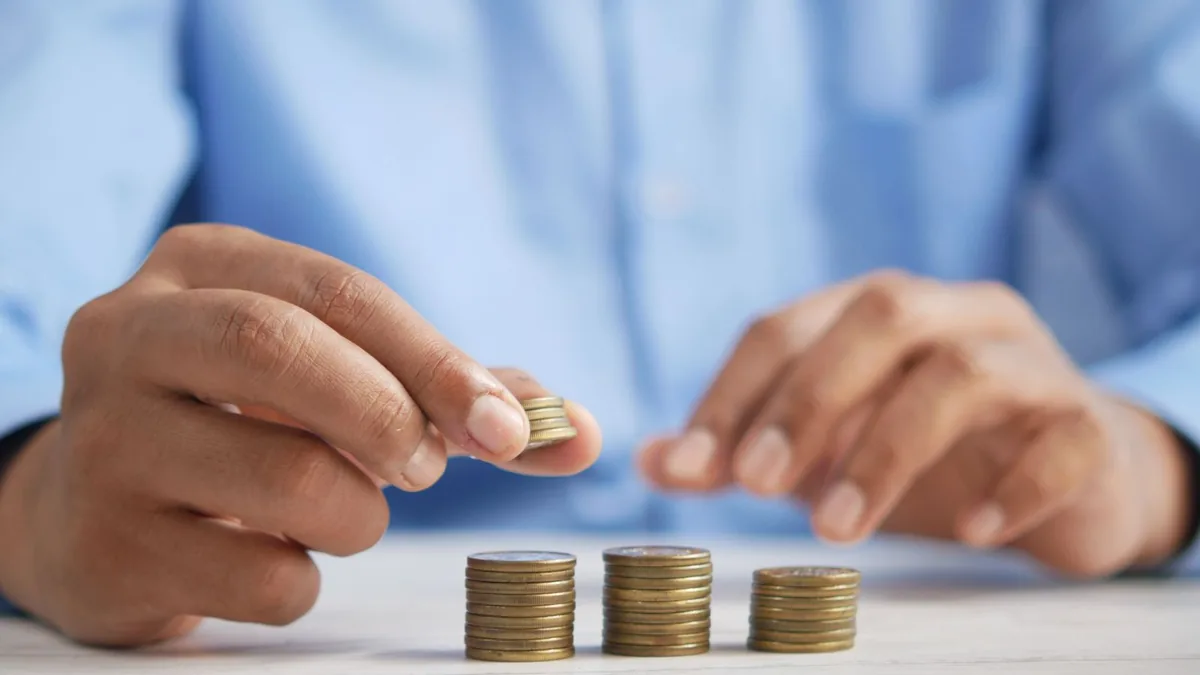 Hands stacking coins in rising columns, showing how MSP SEO cost grows with markets