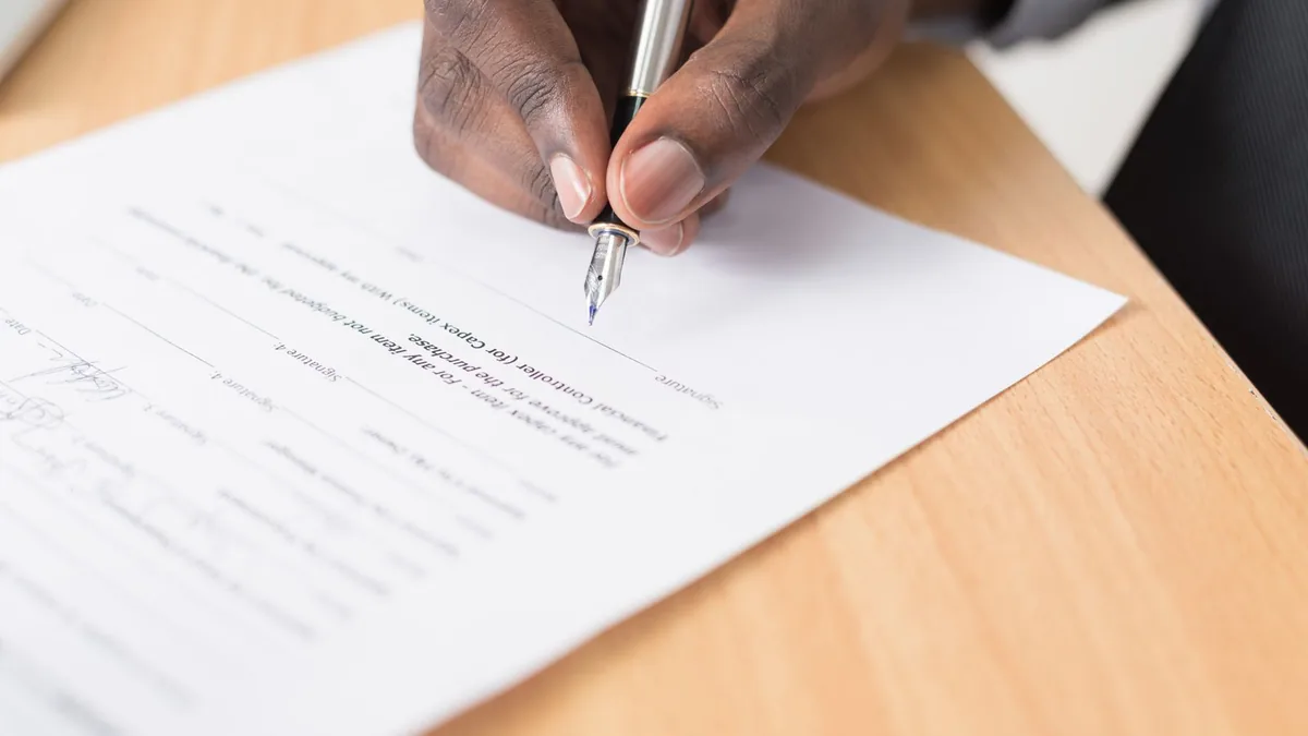 Hand signing a purchase document with a fountain pen, the step where MSP valuation multiples turn into cash