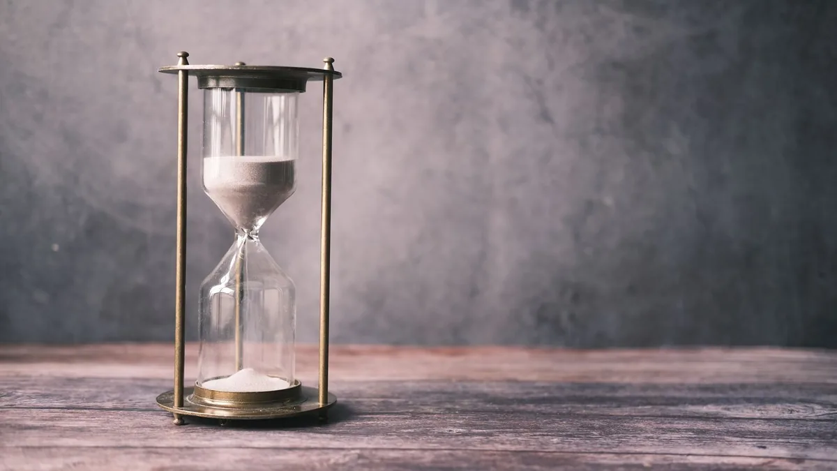 Small business capital advisory concept: a brass hourglass on a wooden table, timing when to raise