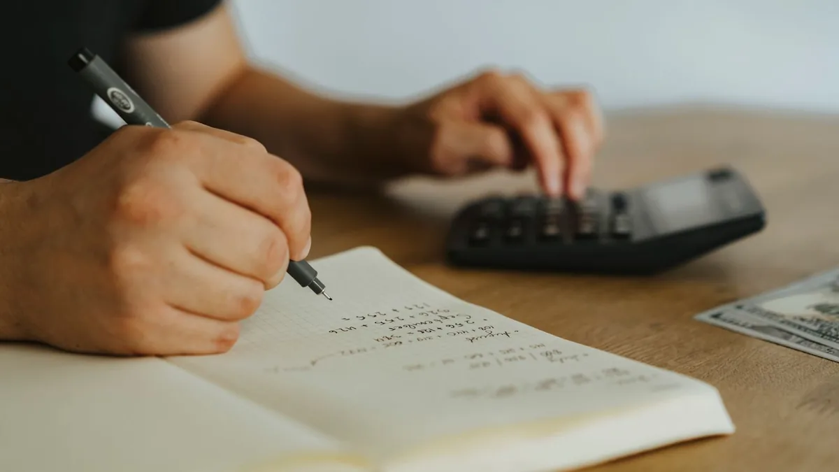 Owner working through figures with a notebook and calculator, the kind of margin question a fractional CFO answers