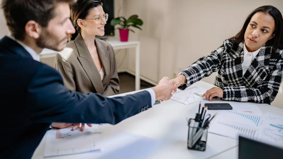 Business people shaking hands over printed charts, the moment an MSP case study helps close