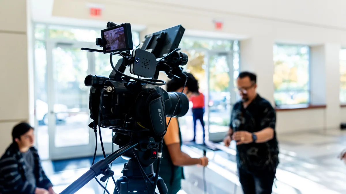 Video camera on a tripod filming a founder in a bright office, the source recording for MSP content repurposing
