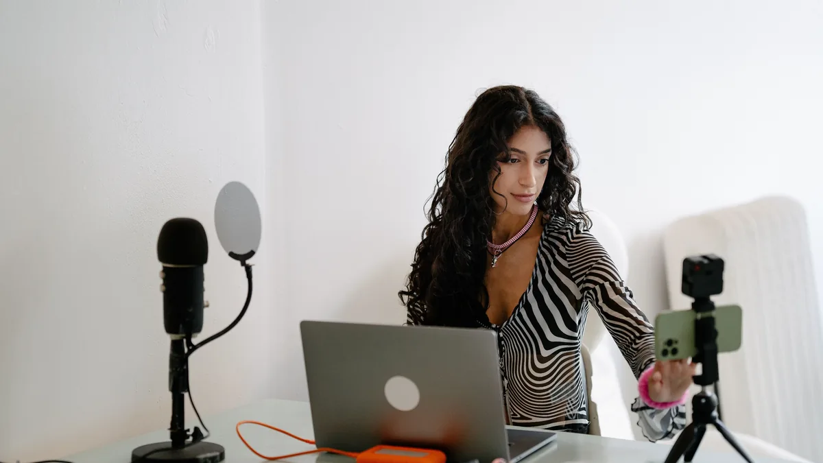 A founder recording at a desk with a microphone and a phone on a small tripod, one recording that becomes many pieces