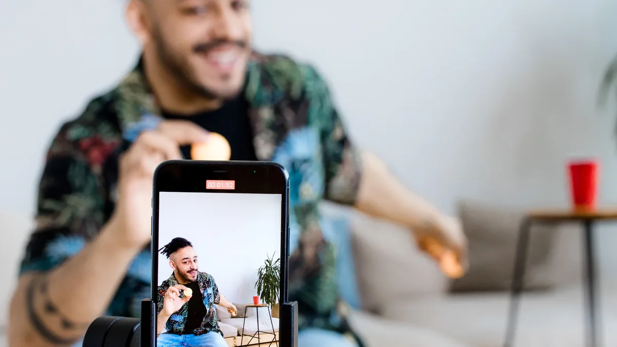 A man filming himself on a phone mounted to a tripod at home, a simple setup for repurposed founder video