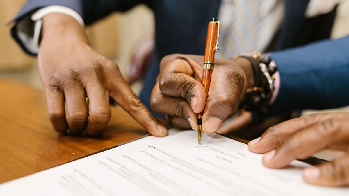 Two people signing a purchase agreement, where MSP earnouts and seller notes are written into the deal