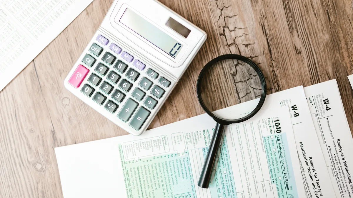 Calculator and magnifying glass on tax forms, the documents a quality of earnings review ties MSP add-backs to