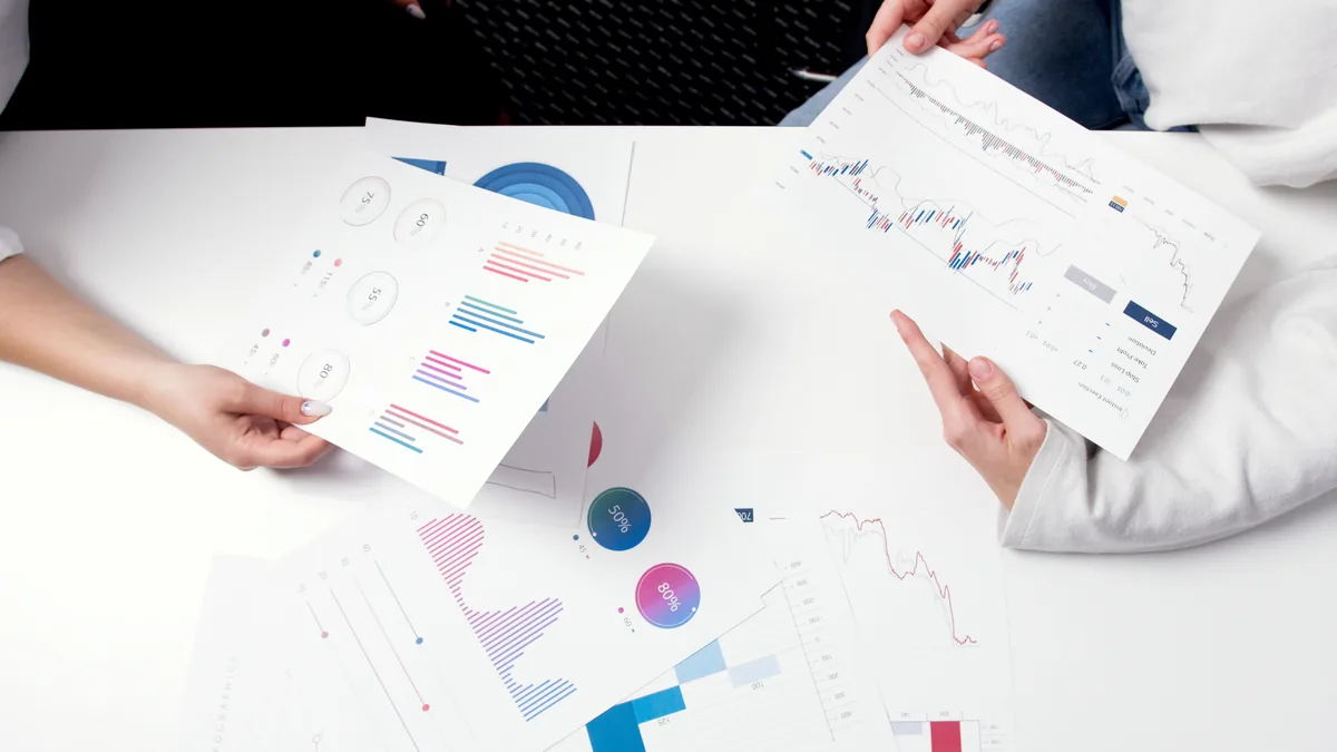 Printed graphs passed across a table, the driver reports behind an MSP financial forecast
