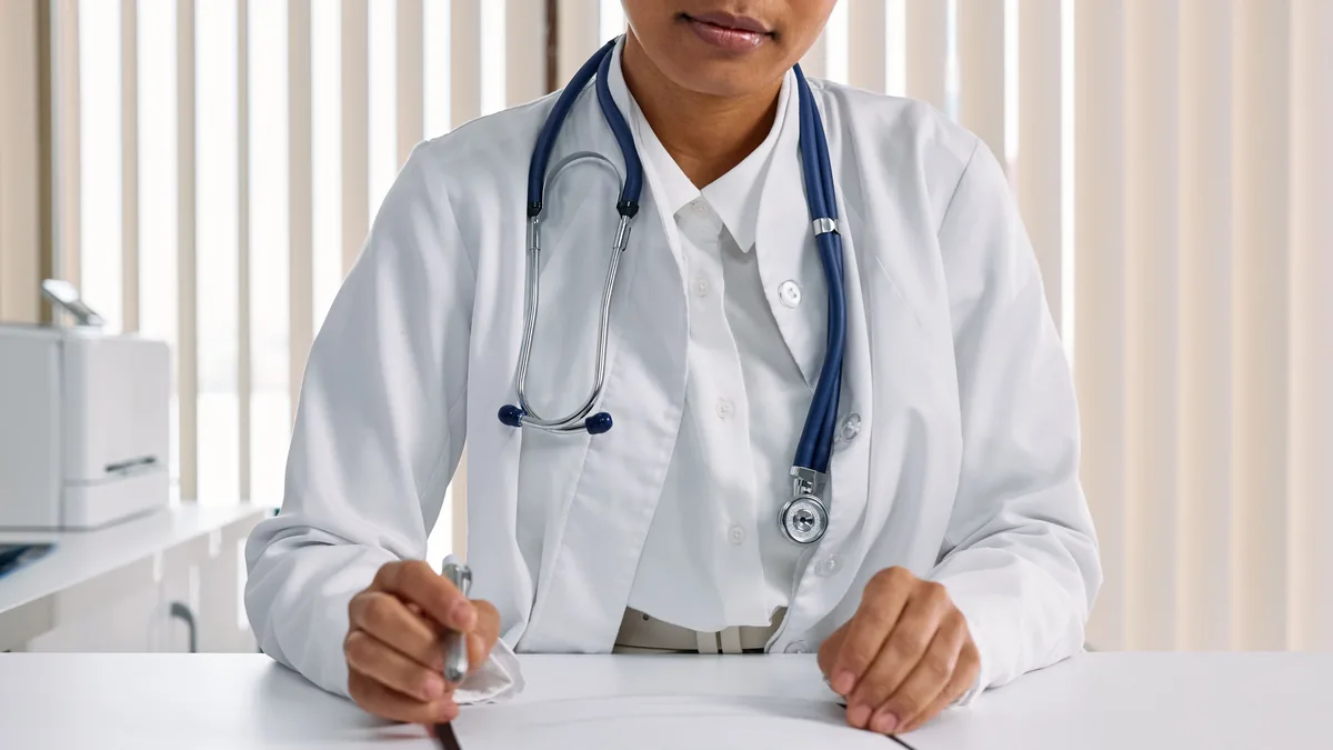 Doctor writing notes at a clinic desk, the kind of healthcare buyer an MSP industry page speaks to