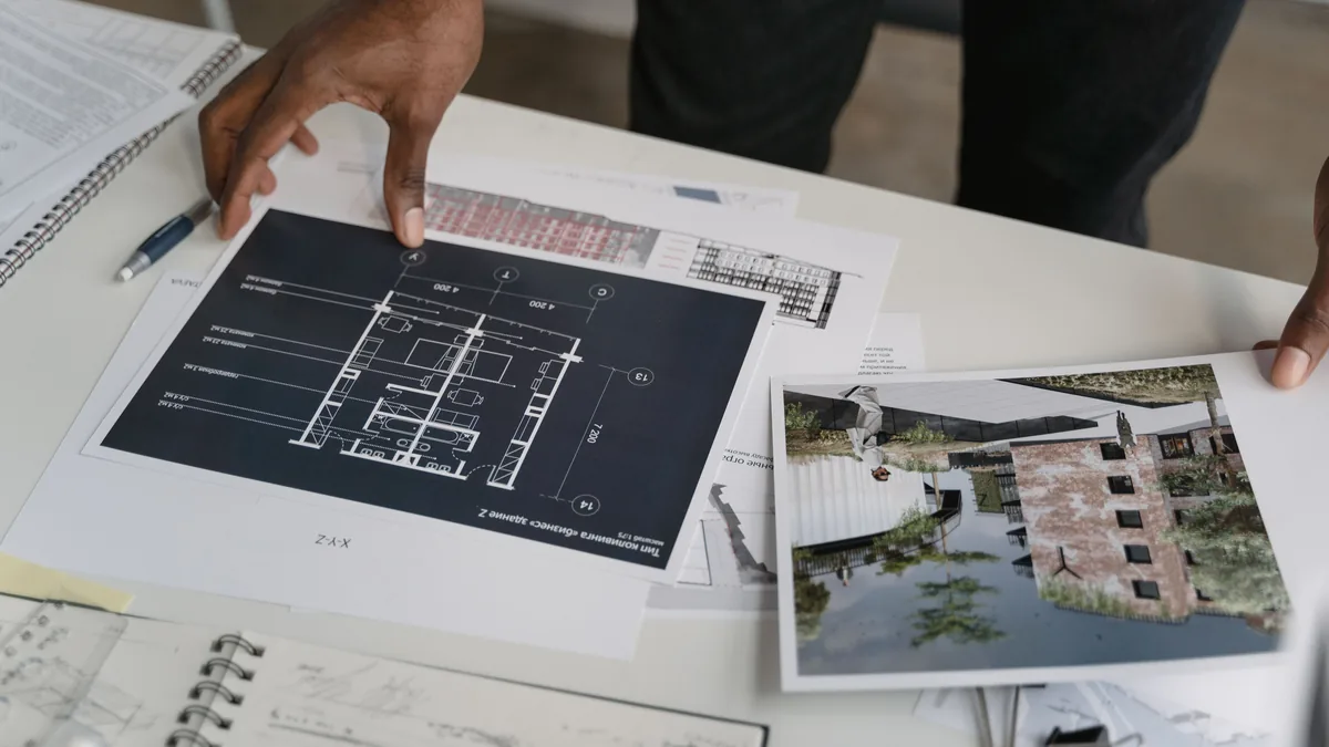 Hands reviewing printed site plans on a desk, a picture of planning MSP service pages
