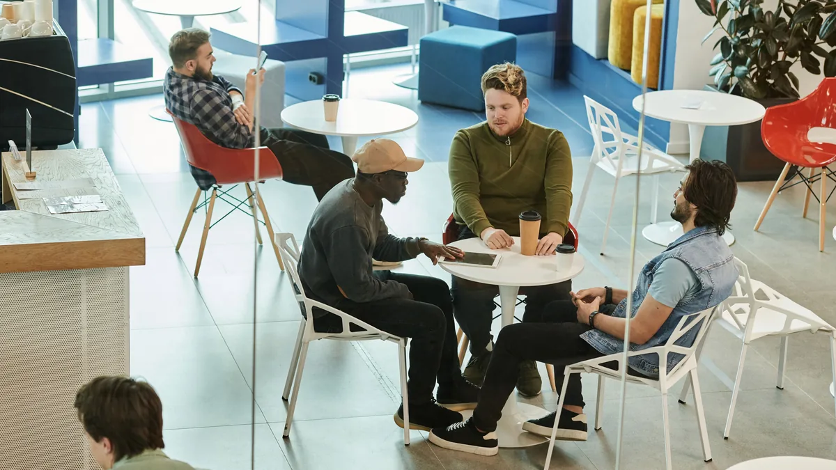 People talking around cafe tables at an informal meetup, the offline version of an online forum thread